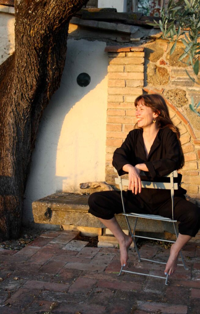 Woman sitting on a chair, smiling, wearing Sulka Viscose Linen Jumpsuit Black